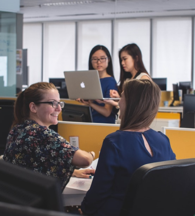 a group of women sitting at a table working on laptops